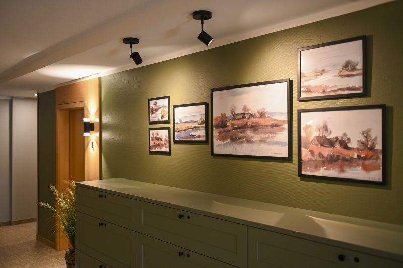 Flur zu den Zimmern mit Kommode, Aquarellzeichnungen an der Wand und stimmungsvoller Beleuchtung