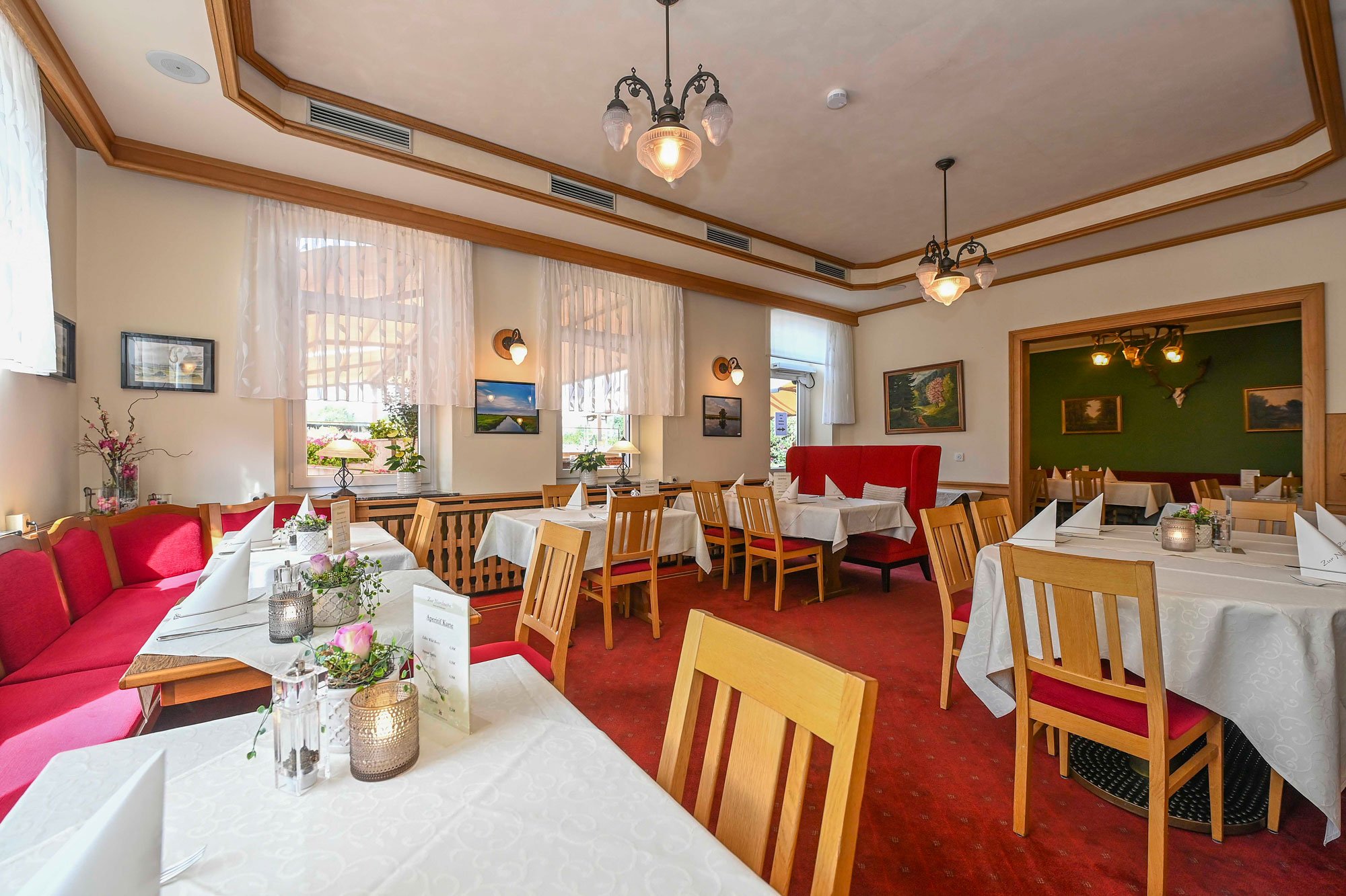 Restaurant - Zur Nordseite Großer Raum des Restaurants mit Tischen und Stühlen, roter Teppich, rote Bänke
