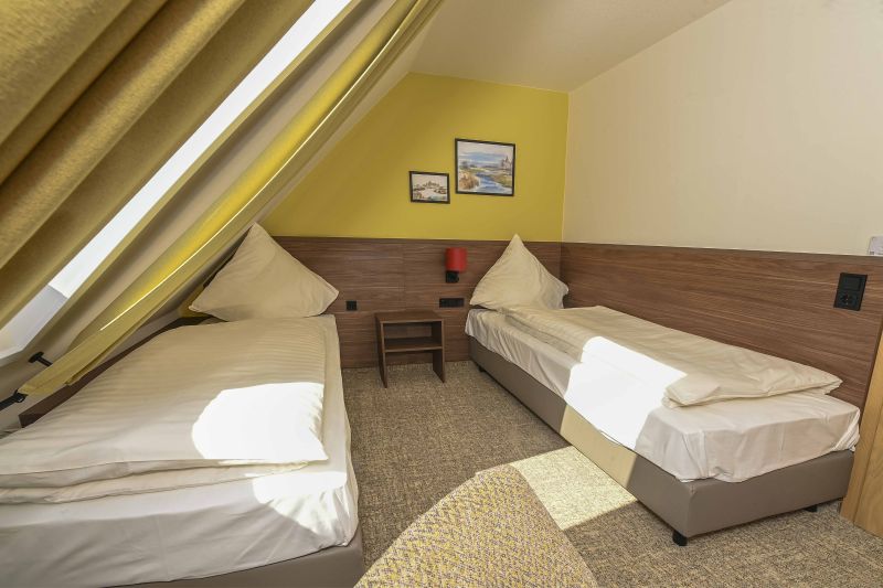 Modern eingerichtetes Doppelzimmer im Dachgeschoss mit zwei Einzelbetten.