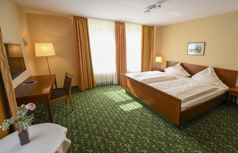 Modern eingerichtetes Doppelzimmer mit Doppelbett, Schreibtisch und Flachbildfernseher.