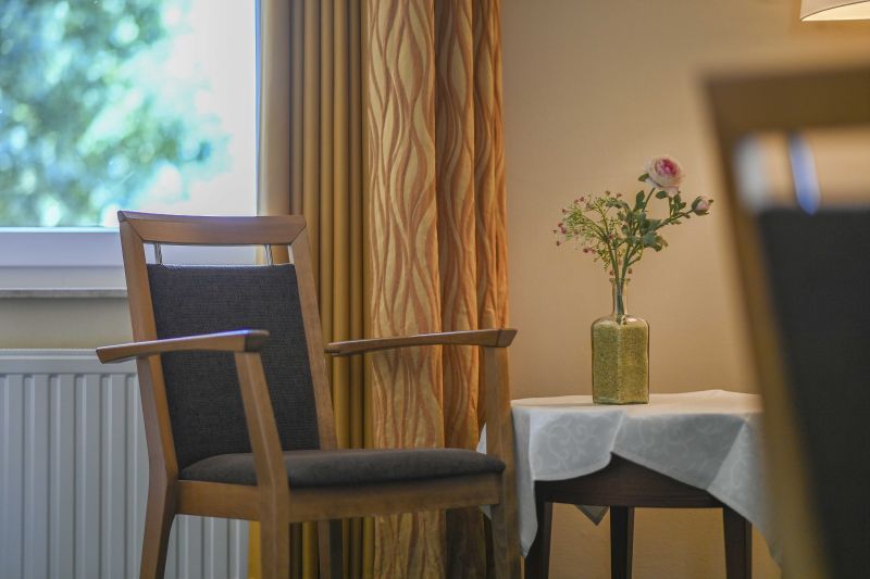 Doppelzimmer Detail, Stuhl und Tisch mit Blumendekoration.