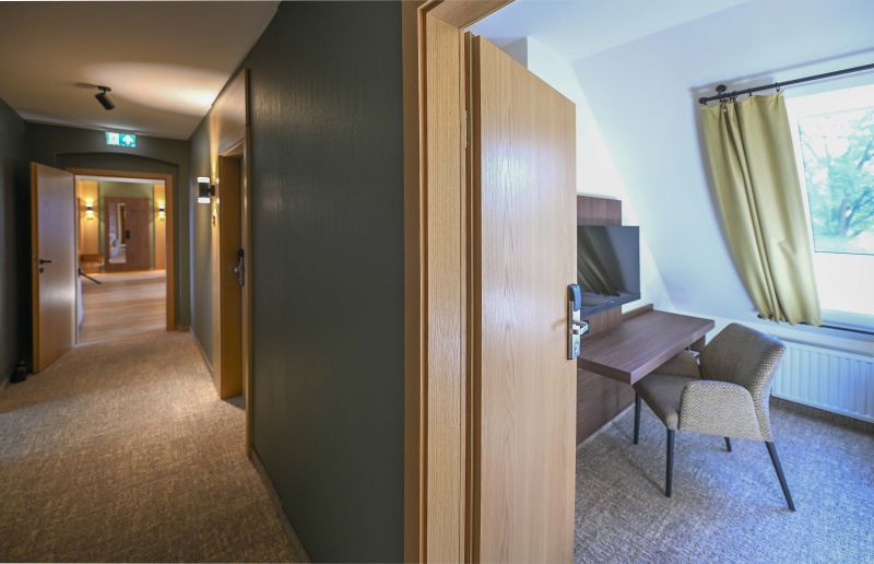 Flur zu den Zimmern im Dachgeschoss mit Blick in eines der Zimmer.