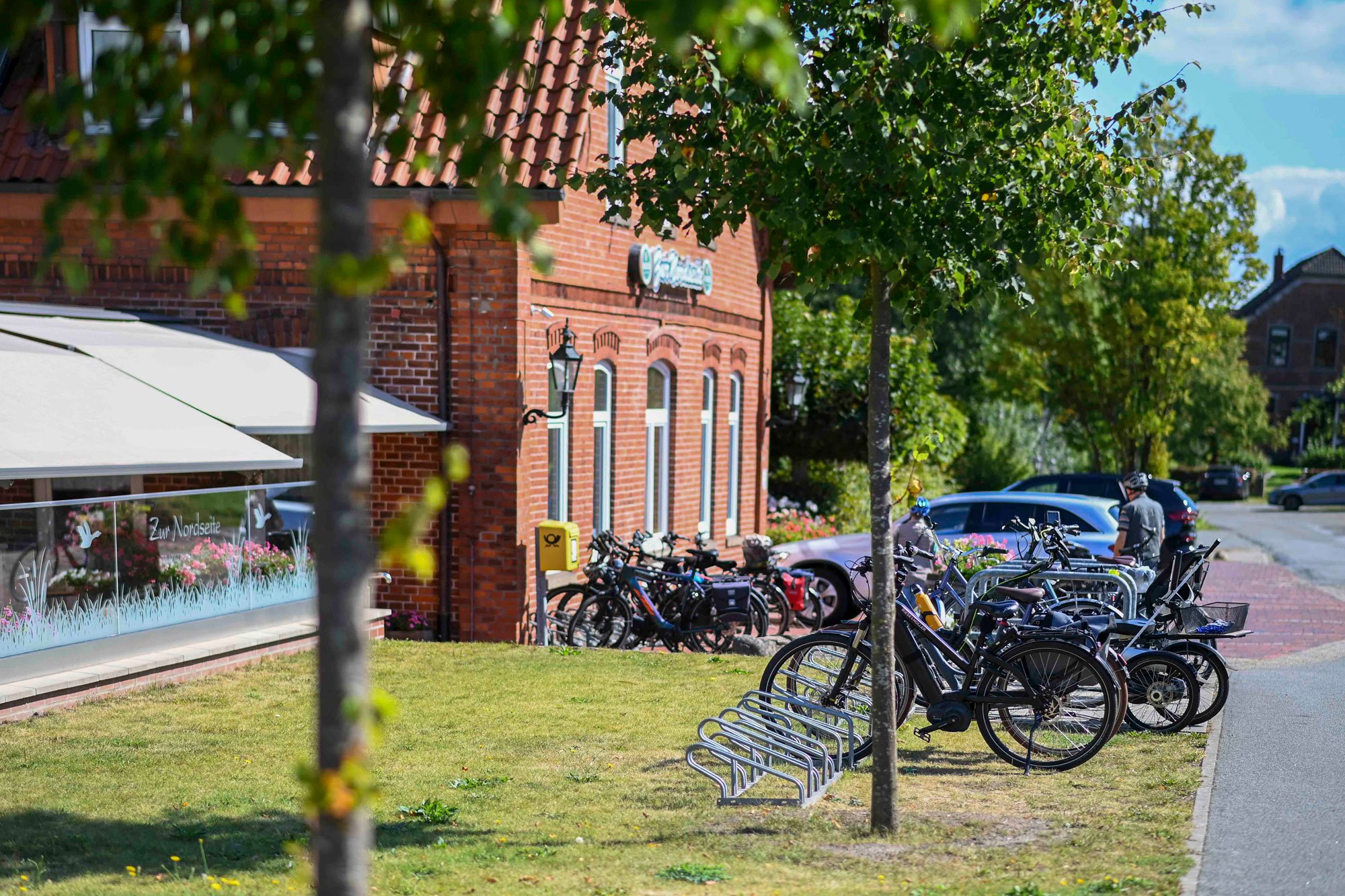 Außenansicht des Gebäudes mit Fahrradständern und Bäumen im Vordergrund