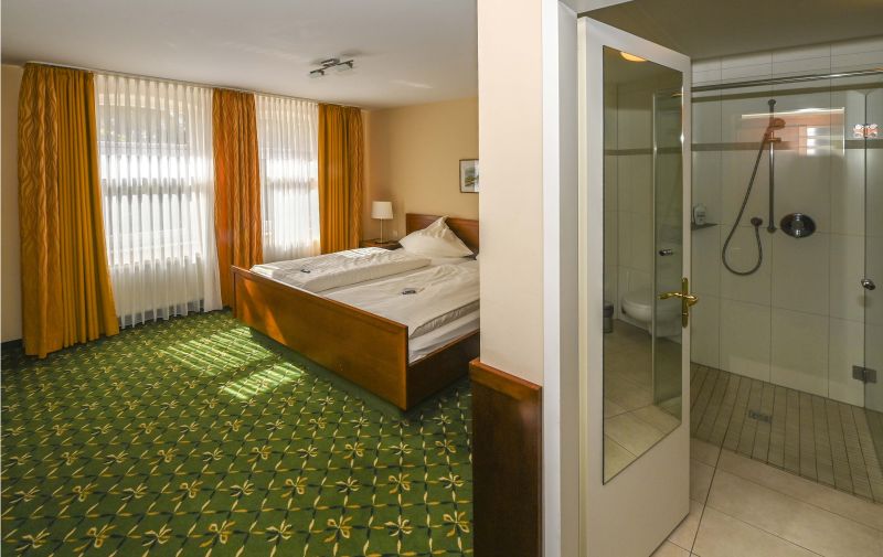 Modern eingerichtetes Doppelzimmer mit Doppelbett und Blick in den Duschraum